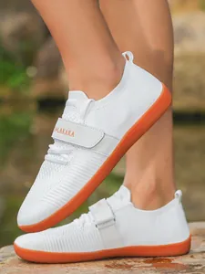 Komfortable weiße Fly-Knit-Walkingschuhe mit breiter Zehenbox und orangefarbenen Sohlen