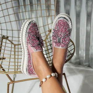 Detail view of pink rhinestone platform loafers with bow decoration on feet