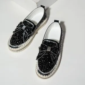 Detail view of black slip-on loafers with sparkling rhinestones and bow decoration