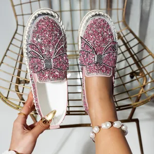 Close-up of pink rhinestone loafers featuring a large bow and sparkly finish