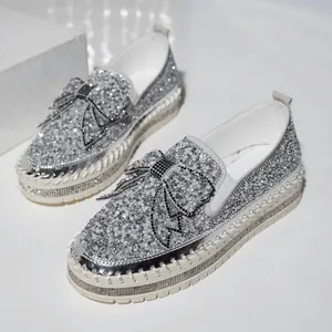 Detailed view of silver rhinestone platform loafers featuring a decorative bow on the toe.