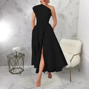 Detail of the elegant one-shoulder black dress with a high-waisted belt and slit