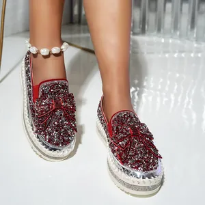 Close-up detail of red loafers with sparkling rhinestone bow and platform sole