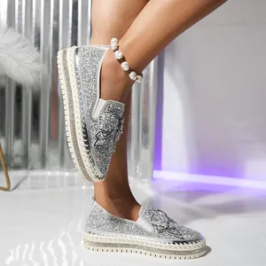 Close-up detail of silver glitter loafers featuring a sparkling rhinestone bow and thick soles