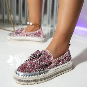 Detail view of stylish pink rhinestone loafers with decorative bow and thick platform soles