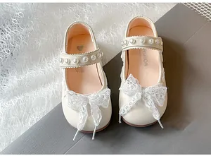 Detailed view of girls beige Mary Jane shoes featuring pearl straps and white lace bows.