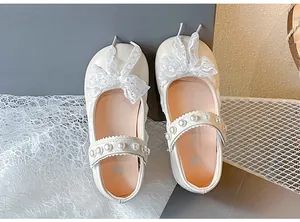 Detail of girls Mary Jane shoes featuring lace bow and pearl-embellished strap in cream.