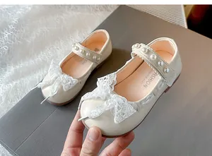 Close-up detail of girls cream Mary Jane shoes featuring lace bow and pearl straps