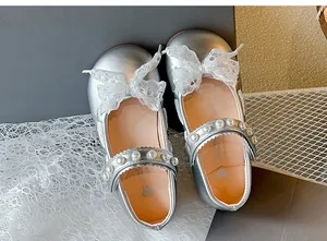 Close-up of silver Mary Jane shoes featuring delicate lace bows and pearl straps
