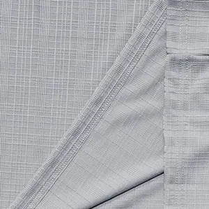 Macro detail of grey slub cotton fabric with textured grid pattern and stitching