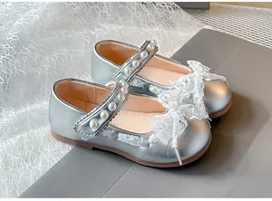 Detail of silver girl's Mary Jane shoes with lace bow and pearl strap embellishments