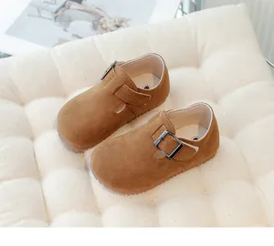 Detail view of brown suede children's shoes with silver buckle on white cushion
