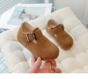 Close-up view of vintage brown suede children's shoes featuring an adjustable metal buckle.