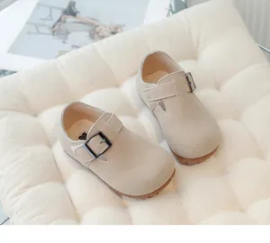 Close-up of vintage beige suede toddler Mary Jane shoes with metal buckle on a white cushion