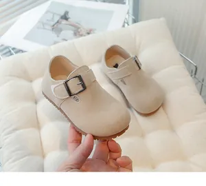 Close-up view of vintage children's beige suede loafers with adjustable buckle strap