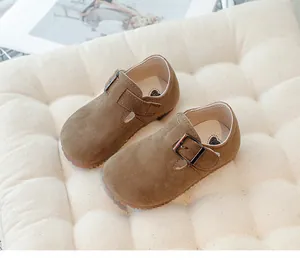 Detailed view of brown suede children's shoes featuring a vintage buckle strap design