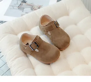 Detailed view of brown suede retro children's T-strap shoes placed on a quilted cushion