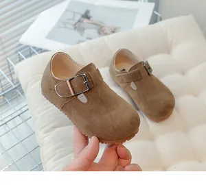 Close-up of vintage brown suede children's shoes with buckle detail on a soft cushion