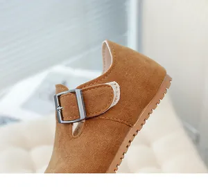 Close-up of brown suede children's shoes showing buckle detail and soft fabric texture