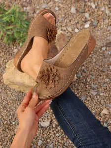 Détail de sandales compensées marron avec fleur décorative et bride perforée