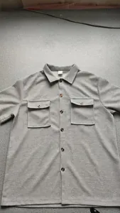 Close-up detail of gray textured fabric and button-down pockets on a men's summer shirt.