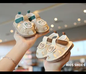 Dettaglio di sandali per bambini con suola morbida, toppe con orsetto e cinturino velcro.