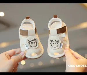 Vista dettagliata dei sandali beige per bambini con orsetto e suole antiscivolo morbide