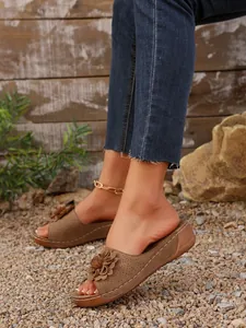 Vue détaillée de sandales compensées marron avec décoration florale et tige découpée au laser