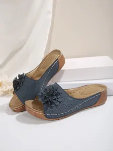 Vue détaillée de sandales compensées bleues avec décorations florales et motifs découpés.