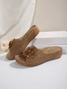 Détail de sandales compensées marron avec bride perforée et grande décoration florale 3D