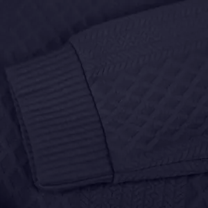 Gros plan sur la texture en maille jacquard bleu marine et le poignet côtelé du sweat-shirt.