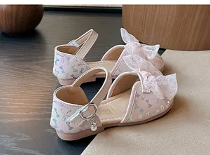 Detailed macro view of pink children's princess sandals featuring lace bows and glitter patterns.