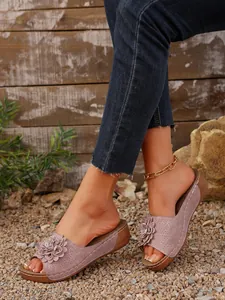 Gros plan de sandales à plateforme mauves avec détail floral et cuir perforé.