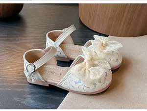 Close-up of cream girls' princess sandals featuring sparkling mesh bows and pearl charms