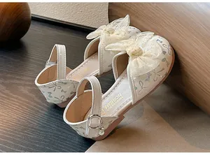 Detail view of elegant cream girls' sandals with delicate mesh bow and pearl charm