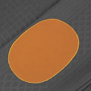 Détail macro montrant un tricot jacquard texturé avec un patch ovale orange vif