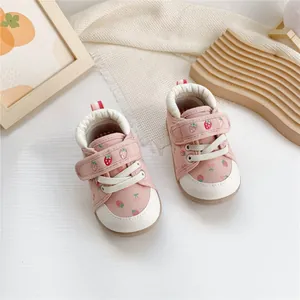 Close-up of pink baby walker shoes with cute strawberry patterns and velcro straps