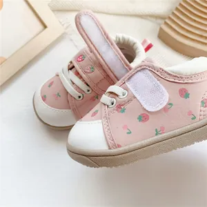 Detail view of pink baby walking shoes featuring strawberry pattern and velcro strap.