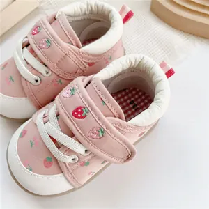 Detail of pink infant walking shoes with strawberry embroidery and hook and loop strap