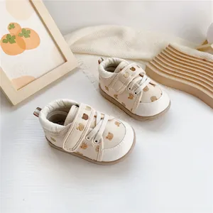 Macro view of cream baby walking shoes featuring a cute bear pattern and Velcro straps