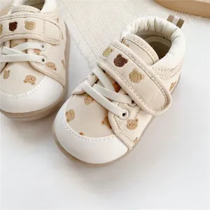 Close-up of beige baby walking shoes with cute bear embroidery and prints