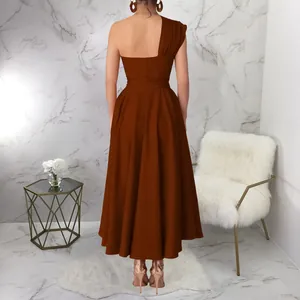 Elegant back view of a brown one-shoulder flared midi dress in a modern marble room setting