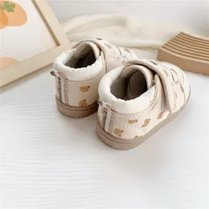 Detail of cream baby walking shoes with cute cartoon bear pattern and velcro straps
