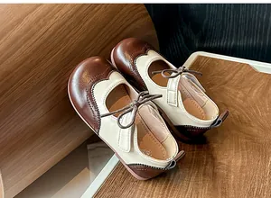Gros plan de chaussures en cuir bicolores pour enfants de style britannique avec brogues.