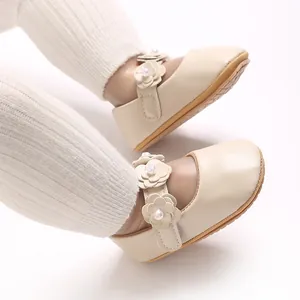 Gros plan de chaussures de princesse pour bébé en PU beige avec fleurs et perles.