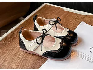 Gros-plan sur des chaussures en cuir bicolores pour fille de style anglais avec nœud