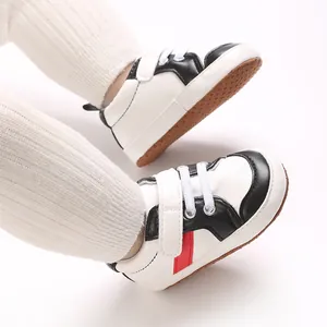 Détail de chaussures de marche pour bébé avec semelle souple et bande décorative rouge.