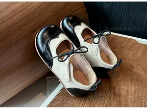 Vue détaillée des Mary Janes bicolores pour enfants avec délicats ornements de nœuds noirs