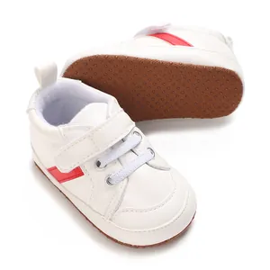 Vue détaillée de chaussures bébé blanches avec semelles souples antidérapantes brunes.