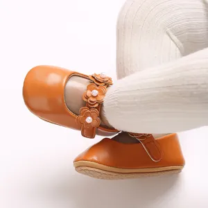 Détail de chaussures Mary Jane orange pour bébé avec fleurs et perles sur collants blancs.